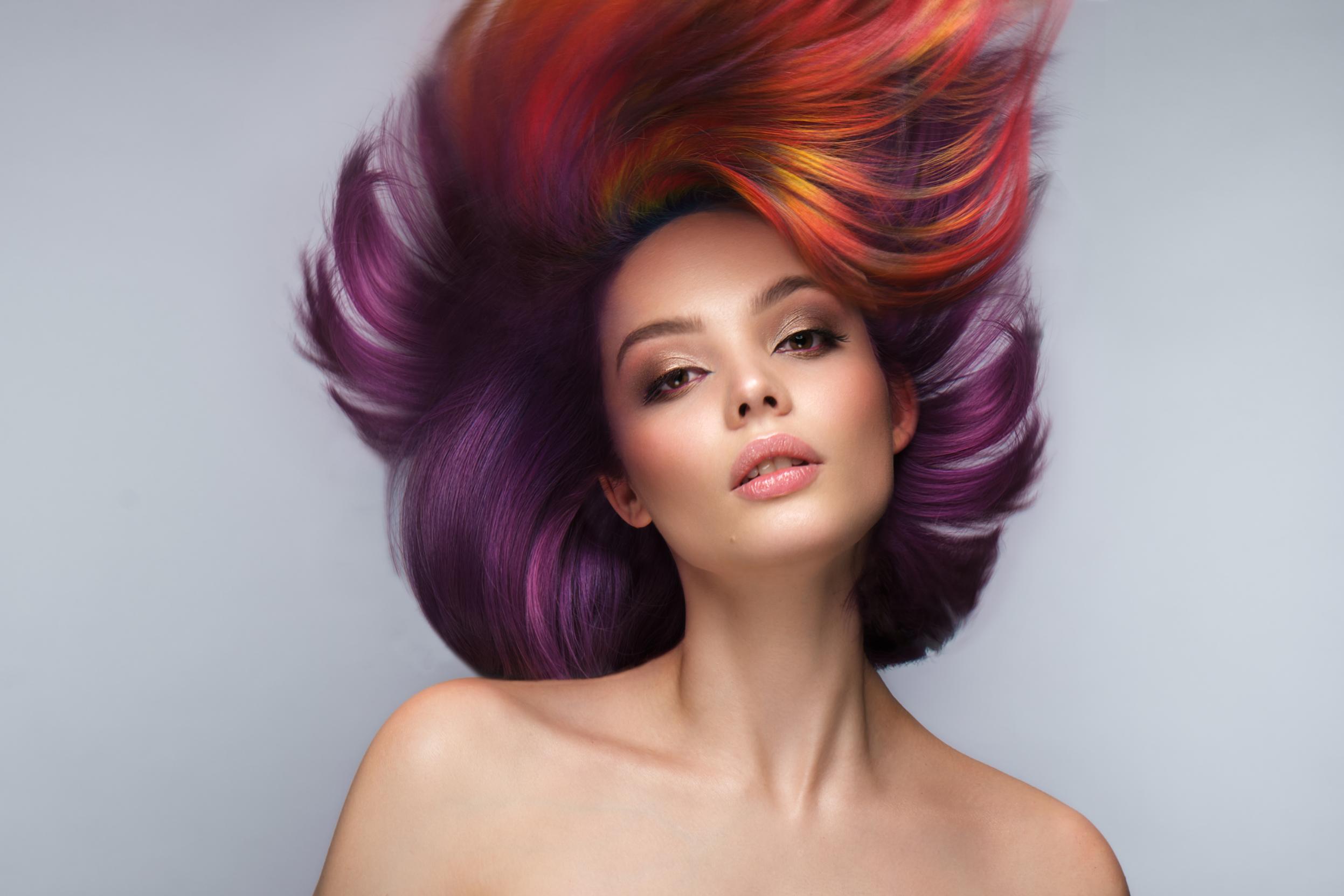 Purple and red hair blowing back from a model's face